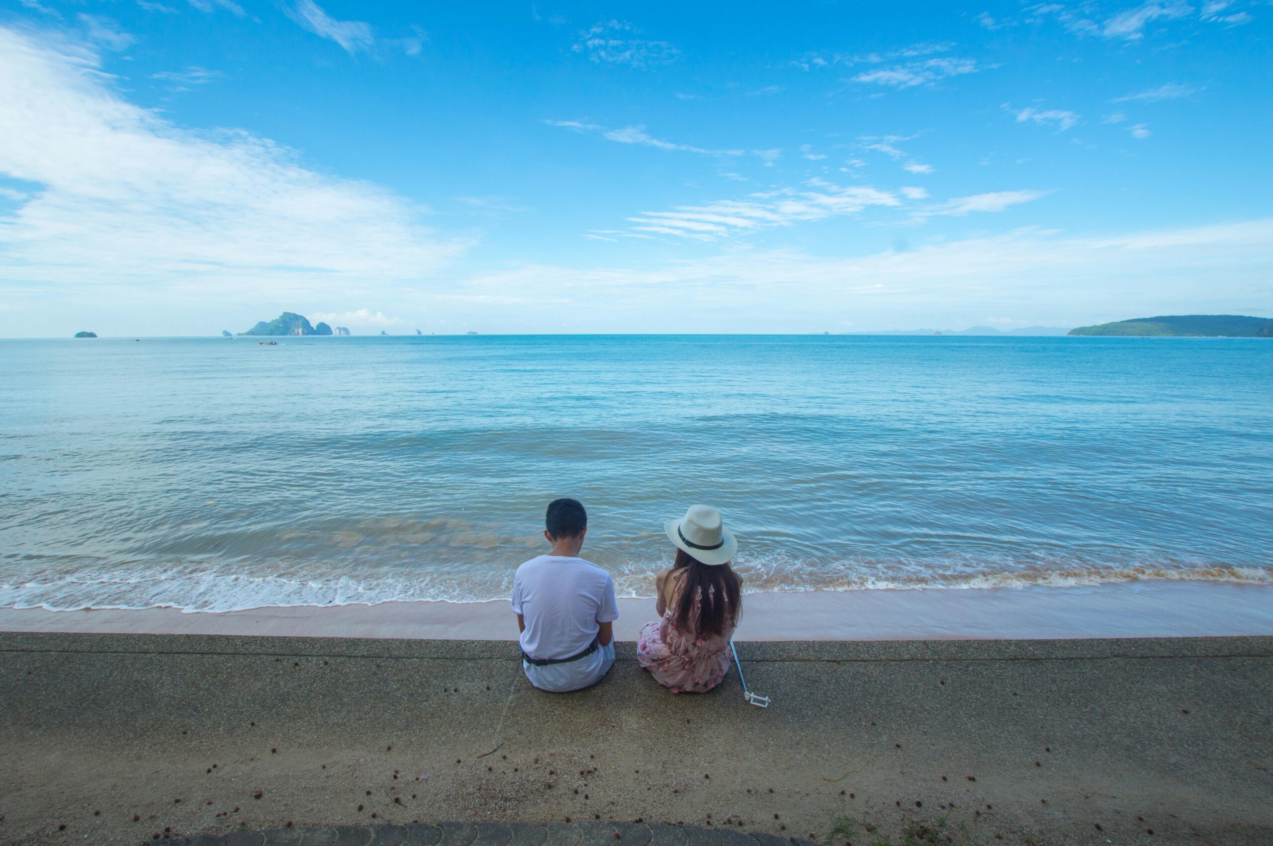 two people sitting looking at the sea with dtv visa thailand