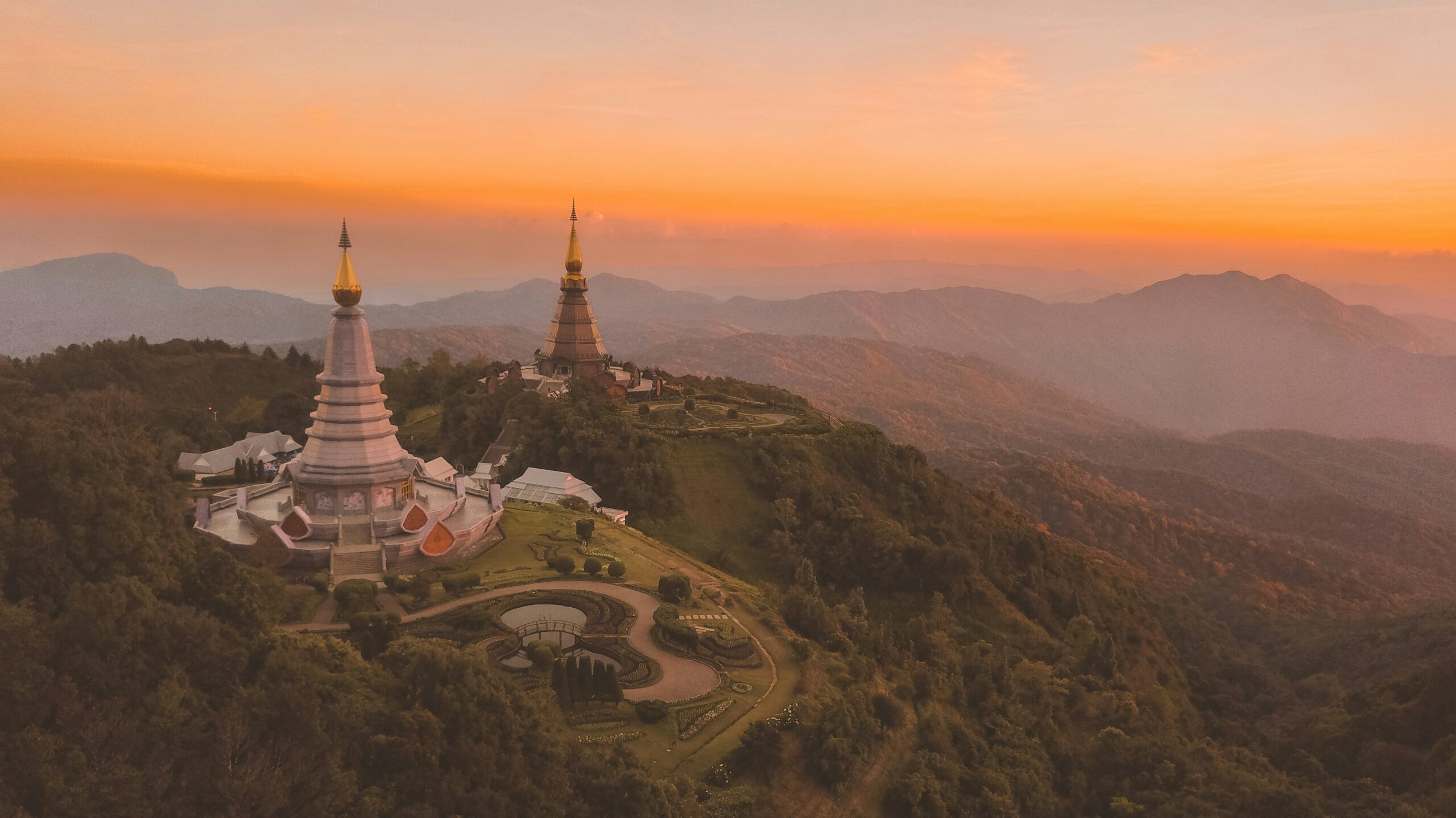 a view of a mountain with two thai temples overlooking a sunset or sunrise